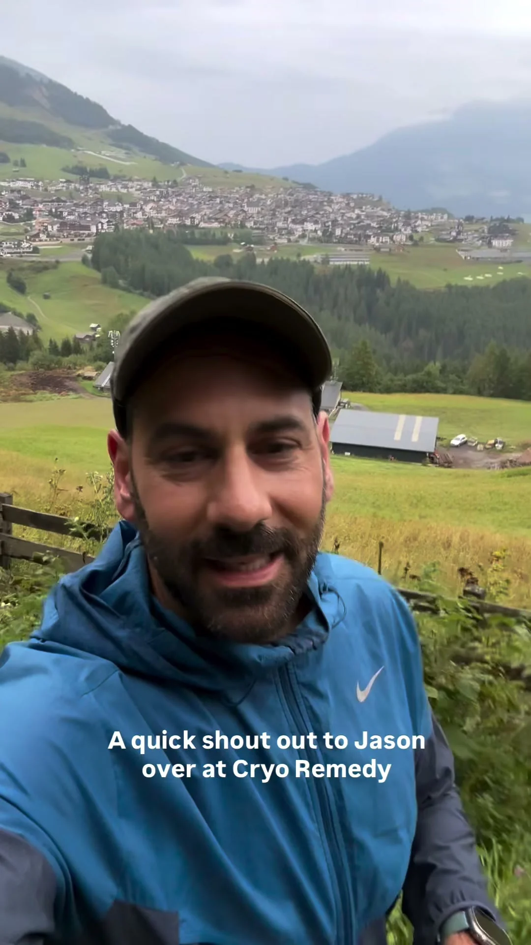 Bill outdoors above an alpine village and green hills